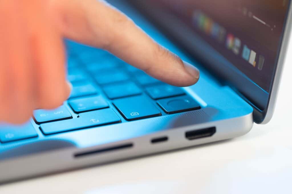 a person pressing a button on a blue laptop
