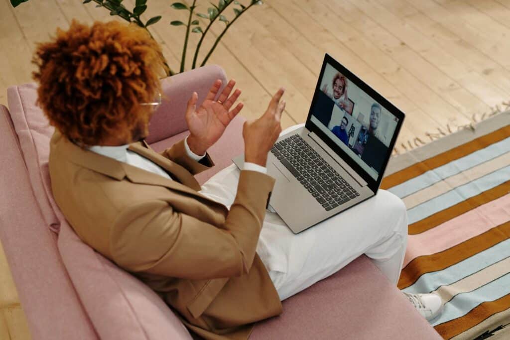 Man Sitting on Sofa Talking on Webcam on Laptop