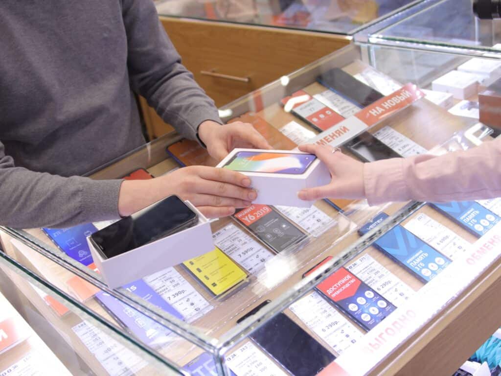 a man and a woman exchanging a cell phone at a store