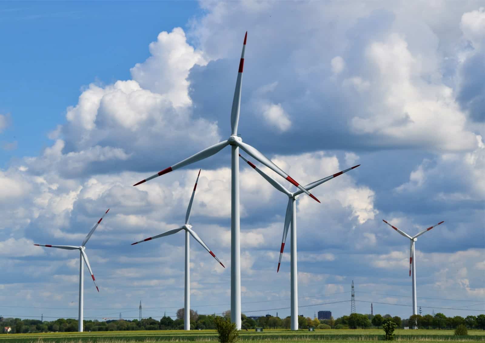 white wind turbines on green grass field under blue and white cloudy sky during daytime